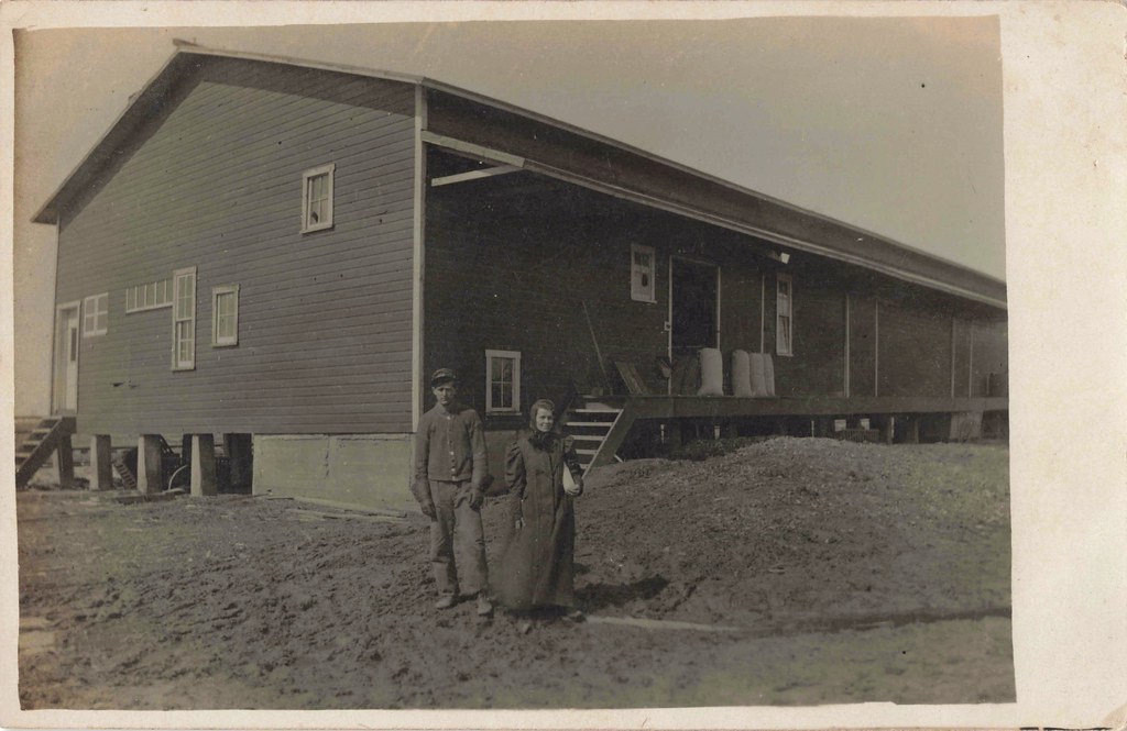 CEN Loomis MI RPPC Young Married Isabella County Couple Man a Feed Mill Granary or Railroad Employee in CUFFED GLOVES near the PMRR Pere Marquette DEPOT which ran between Midland & Clare near Coleman
