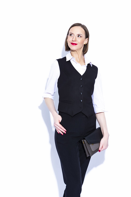 Smiley Portrait of Positive Confident Caucasian Business Woman in White Shirt Posing With Clutch On White