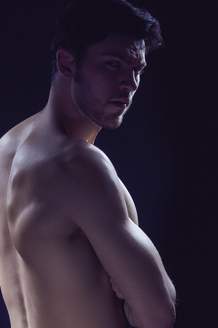 Closeup Image of Confident Thinking Caucasian Bodybuilder Athlete Man Posing With Naked Torso Against Dark