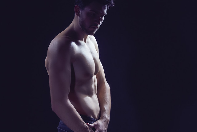 One Confident Thinking Caucasian Bodybuilder Athlete Man Posing With Naked Torso Against Dark