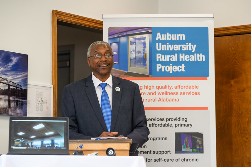 A man stands at a podium smiling in front of a sign that says Rural Health