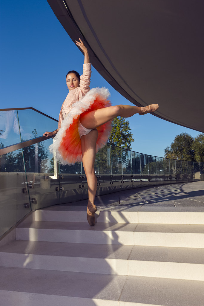 Dance Sport Ideas. Winsome Sexy Slim Professional Caucasian Ballet Dancer in Pink Tutu Dress Posing in Leg Muscles Stretching Pose On Stairs