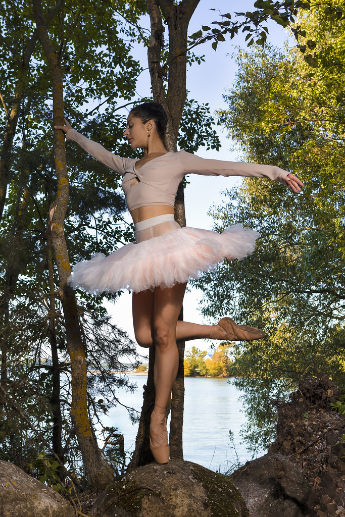 Sexy Caucasian Ballet Dancer in Rose Pink Tutu Posing During Ballet Pas On Stone in Summer Forest Against Forest With Lifted Hand