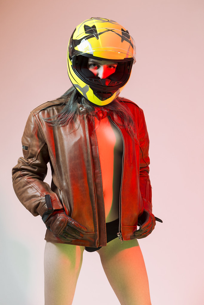 Sensual Sexy Caucasian Female Motorcyclist Posing In Leather Protective Jacket And Helmet Over Yellow