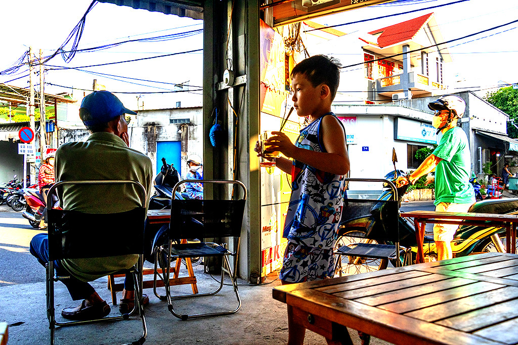 Boy clearing a table after being gently urged by his mom at Bitter Coffee on 2-24-24--Vung Tau copy