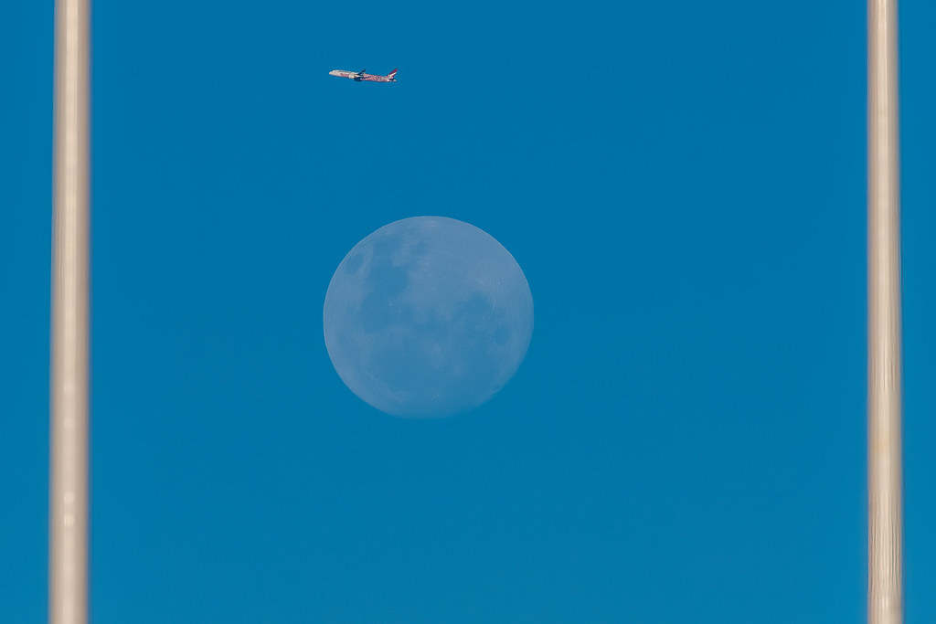 Between the goal posts - Qantas Airplane and nearly a full moon rising in the blue afternoon sky