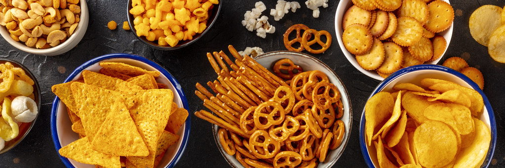 Salty snacks, party mix panorama. An assortment of crispy appetizers