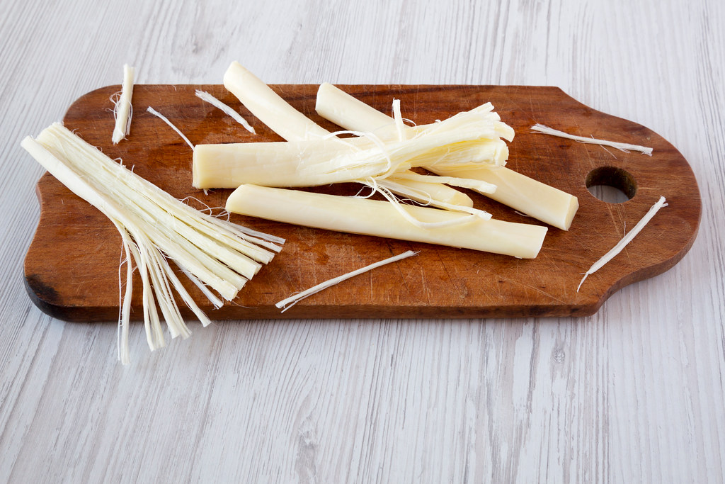 String cheese on rustic wooden board, side view. Healthy snack. Closeup.