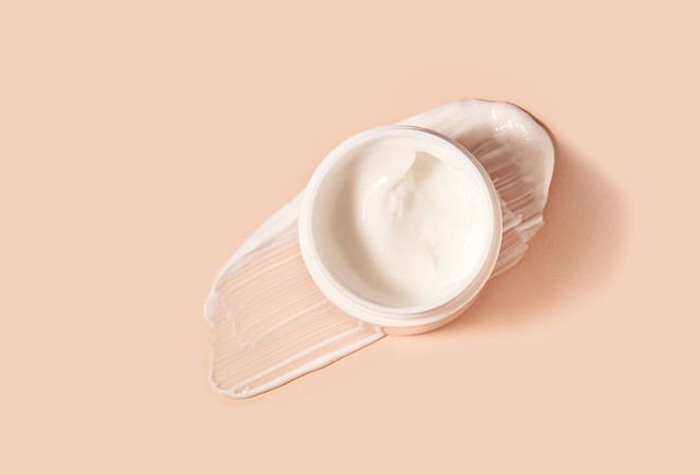 White smeared cream or cosmetic face mask with the open cosmetic jar.  Purifying and moisturizing cream. Flat lay