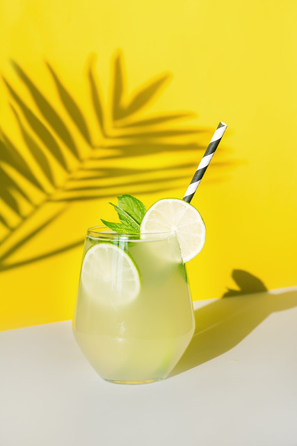 Fresh summer lemonade with lemon, lime, orange and mint on yellow background.