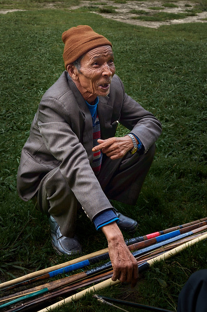 Teer, Shillong. After the contest an elderly gentleman squats on the grass near his bows and arrows.