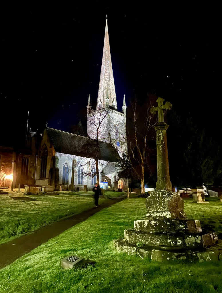A photo of a church, illuminated against the night sky, with a tall pointed spire.