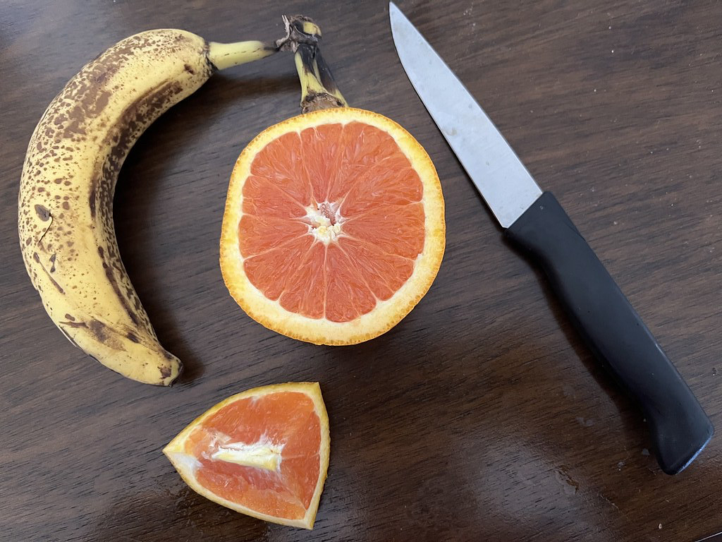 Ripe Banana & Cut Orange On Table With Knife - Natural Still Life Photo Taken by STEVEN CHATEAUNEUF On March 12, 2024