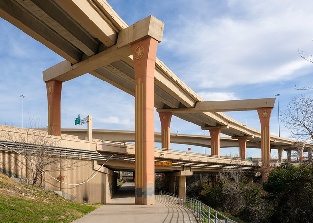 See orange and yellow columns of precast concrete, supporting a flyover ramp at a stack interchange on Interstate 635 in beautiful Dallas in February sun.
