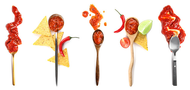 Collage of spoons with tasty salsa sauces and nachos on white background