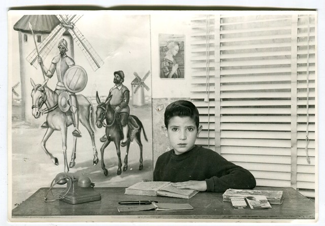 Retrato escolar de un niño junto a un cuadro en el      que aparecen Don Quijote y Sancho Panza