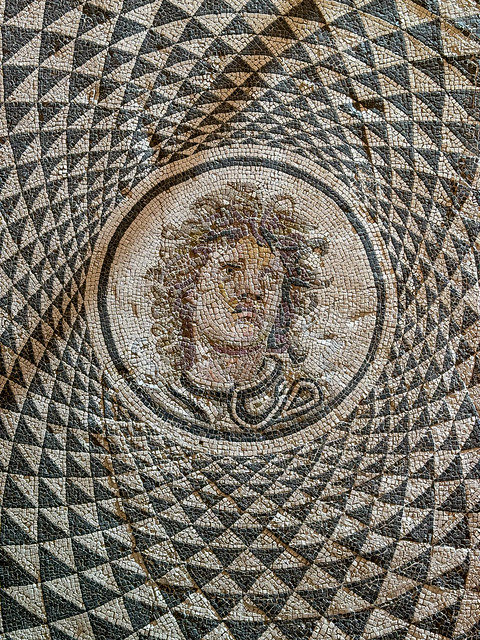 Closeup of a round geometric mosaic, with the head of Medusa