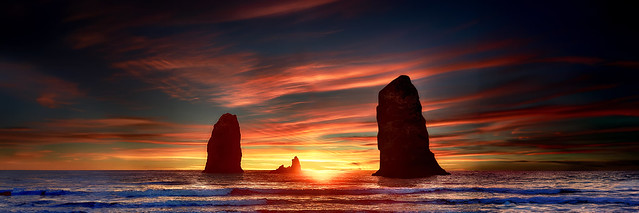 Cannon Beach sunsets paint the sky as waves roll against the rocks, creating a mesmerizing symphony of nature.