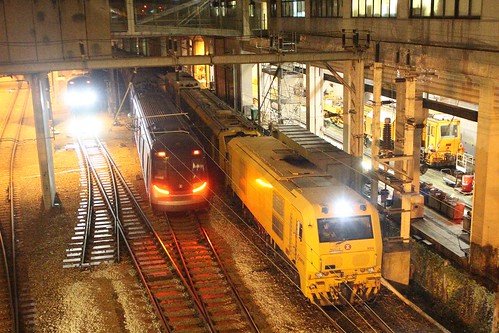 MTR Hyundai Rotem EMU passes MTR MTR CKD0A diesel-electric locomotive 9004 and classmate with a rail grinder at Ho Tung Lau depot