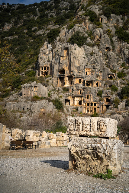 Sculpture of Greek theater masks against Myra's cliff tombs.