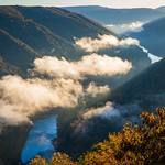 Floating through New River Gorge NP In the early morning light, as the New River water flows through West Virginia&#039;s New River Gorge National Park and Preserve, clouds float above it, also passing through the gorge.