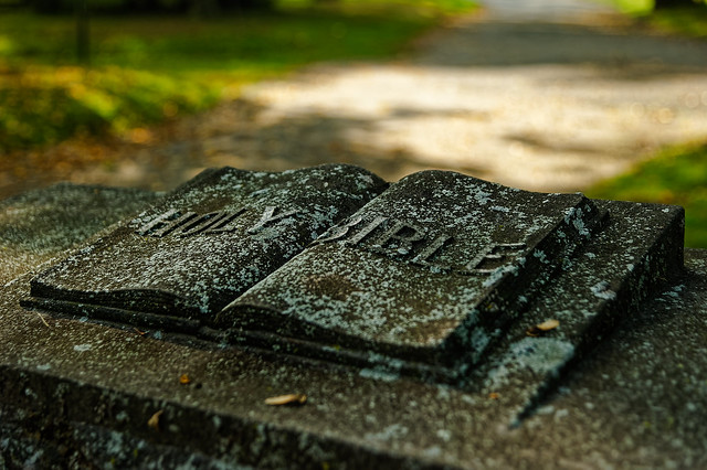 A stone sculpted Holy Bible lays open on to of a grave marker