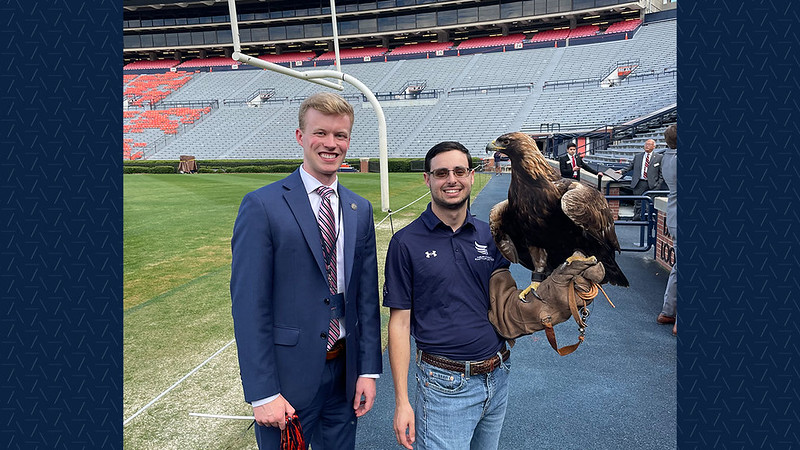 Jack Hilton poses with Auburn's golden eagle Aurea and a Southeastern Raptor Center staff member.