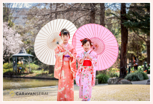 sisters posing in a kimono with a Japanese umbrella against a backdrop of cherry blossoms