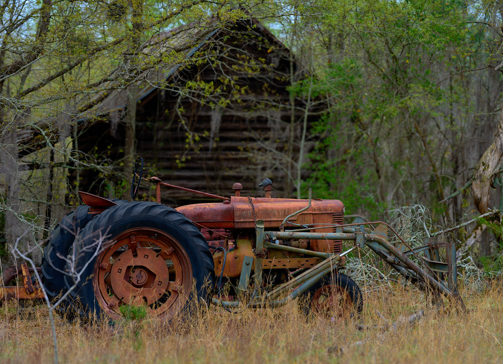 old farmall tractor by a log shed