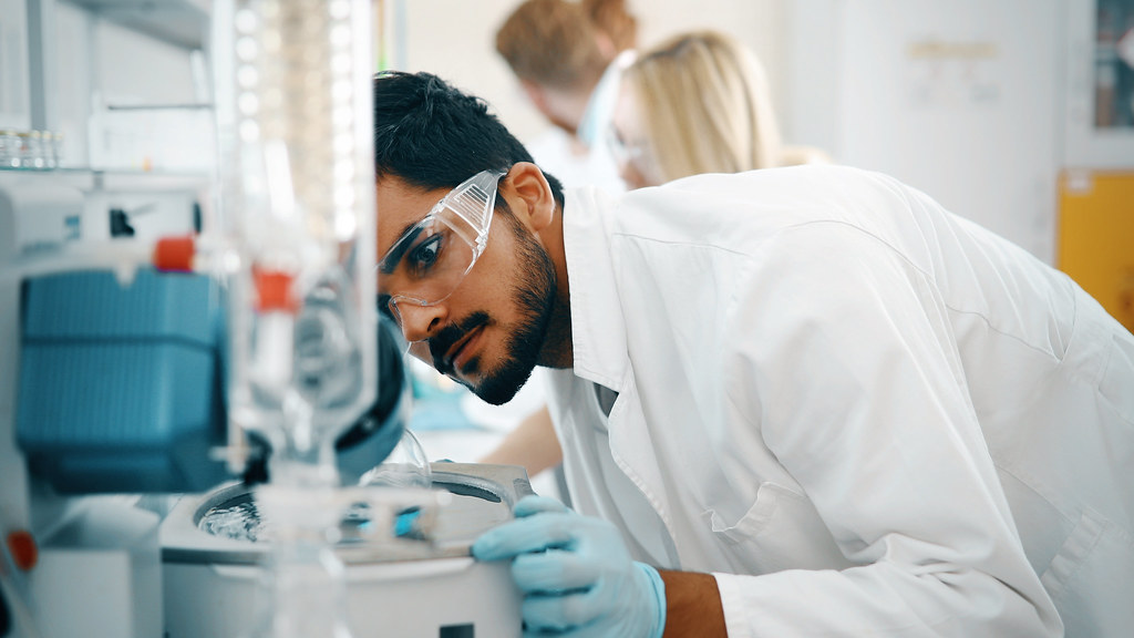 A researcher wearing goggles, working in a lab