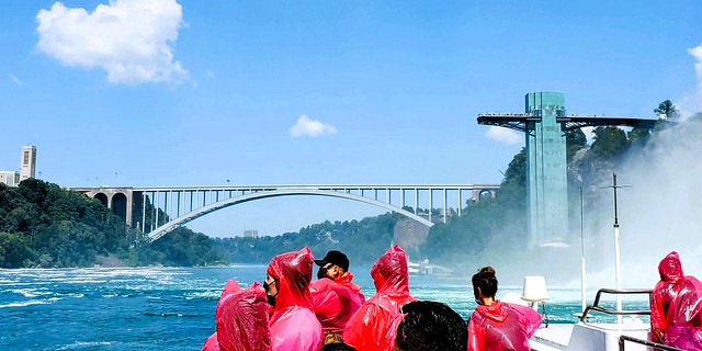 People aboard the Niagara City Cruises (Niagara Hornblower) boat heading towards Prospect Point and the Rainbow Bridge; view of both Niagara Falls