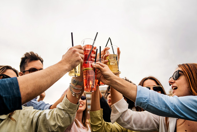 Group of friends joining cocktail glasses outdoors - Young people drinking alcohol drinks and toasting together