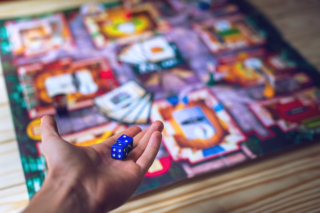 Hand throws the dice on the background of Board games