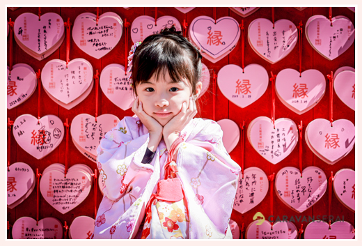 Pose with a pink heart ema as the background