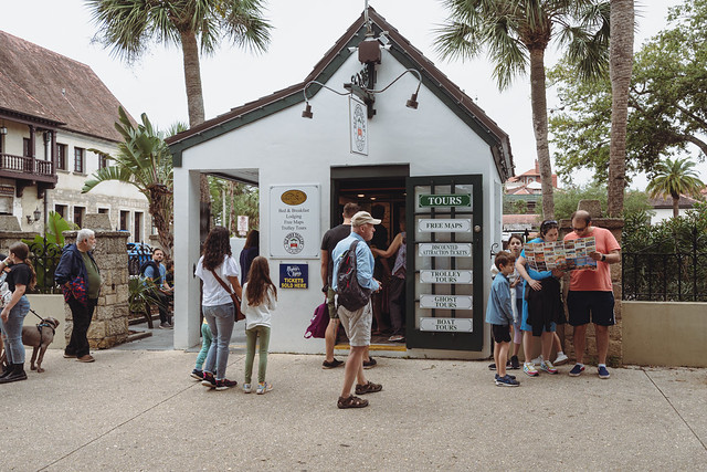 St. Augustine, Florida - December 31, 2022: Tourists linger around the Old Town Trolley information visitors booth, looking and reading maps of the local attractions