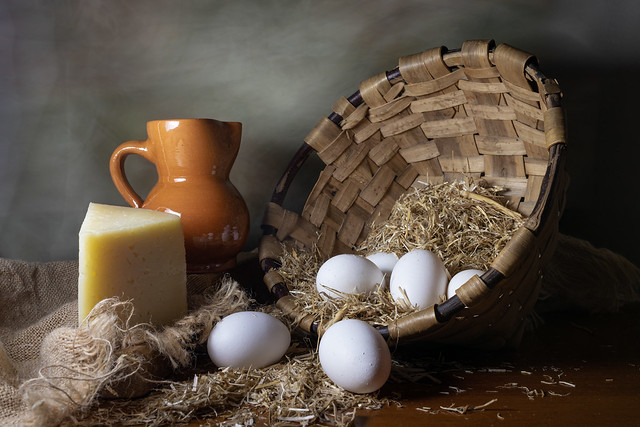 Bodegón clásico con huevos, queso y jarra de vino