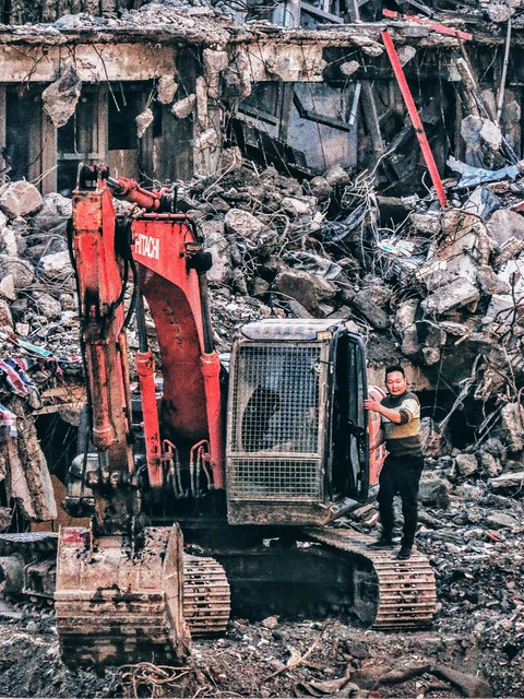 An excavator and its operator at a demolition site