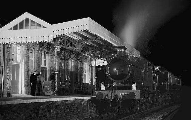A porter looks on as GWR Collett 2251 Class 0-6-0 no.3205 waits with its short passenger train by the platform of Winchcombe Station on the evening of 7th October 2000