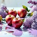 Five apples on a table covered in paint, surrounded by lilac flowers in natural light
