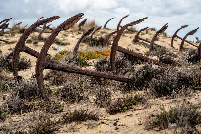 Rusty old anchors on the beach at the Anchor Cemetary graveyard at Praia do Barril beach, in Tavira, Algarve, Portugal