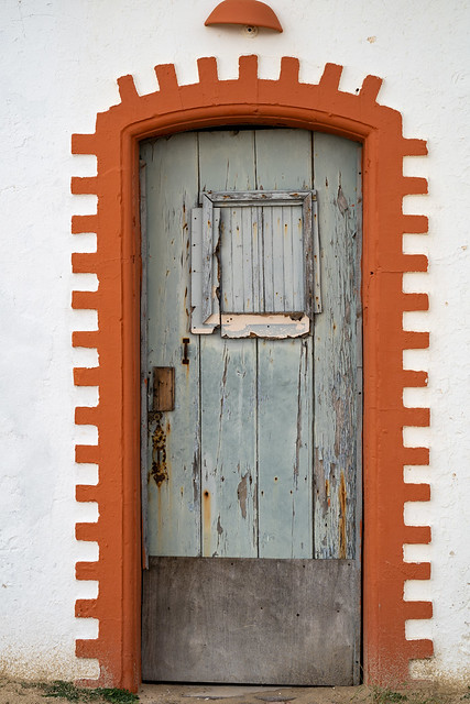 Orange door of the former whitewashed fishermen huts at Praia do Barril beach, in Tavira, Algarve, Portugal