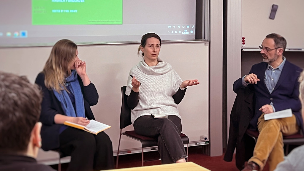 People talking to a crowd of other people in a room.