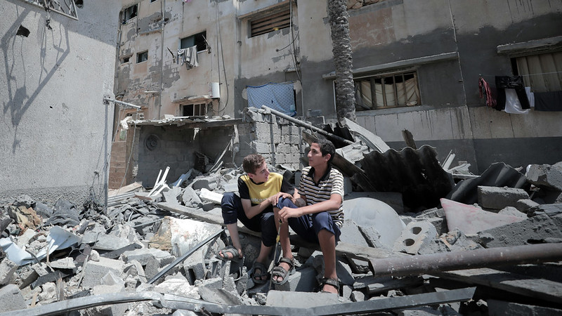 Two boys sat on a mound of rubble in a demolished neighbourhood