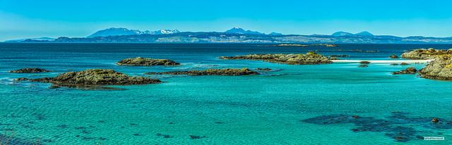 Blue heaven. Eight people on a Tombolo beach and two on the skerries. Sleat Peninsula, Cuillins of Skye, from the skerries and beaches of the Arisaig/Morar coast on a warm spring day.