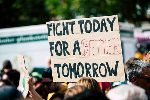 A protester holds a sign that reads "Fight today for a better tomorrow" - How to Contact Your State & Local Reps to Push for Social Justice