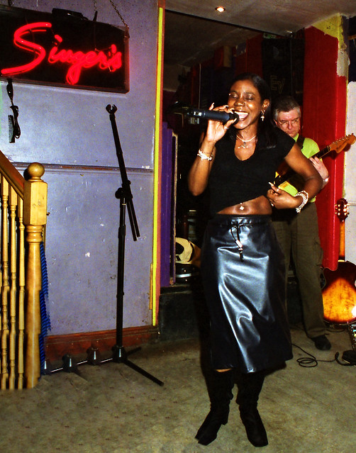 Charming Cat Eyes Lady in Black PVC Skirt with Bare Midriff Exposing Her Navel Jewellery at Singers Open Microphone with Asha on Keyboard The Spot Maiden Lane Covent Garden London West End October 2001 008v