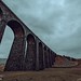 The Ribblehead Viaduct or Batty Moss Viaduct carries the Settle-Carlisle railway across Batty Moss in the Ribble Valley at Ribblehead, in North Yorkshire, England. The viaduct, built by the Midland Railway, is 28 miles north-west of Skipton and 26 miles 
