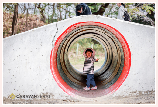 公園のトンネルで遊ぶ小さな女の子