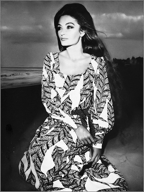 Anouk Aimée in ankle-length dinner dress with deep décolletage, high-waisted and balloon-sleeved, printed with enormous brown feathers by Bill Blass for Maurice Rentner, photo by Hiro, Harper's Bazaar, April 1969