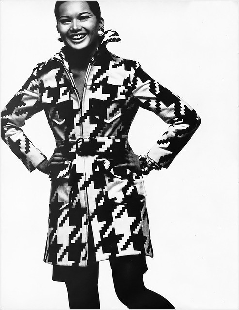 Model in raincoat in oversized houndstooth pattern, zipped over straight black short pants, by Modelia, photo by Bill King, Harper's Bazaar, April 1969